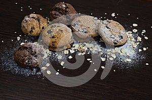 Cookies with chocolate on dark background with sugar powder, oat flakes, seasame and almond. Copyplace, place for text. Sweets