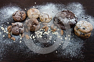 Cookies with chocolate on dark background with sugar powder, oat flakes, seasame and almond. Copyplace, place for text. Sweets