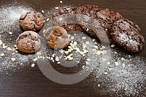 Cookies with chocolate on dark background with sugar powder, oat flakes and seasame. Place for text, copyplace