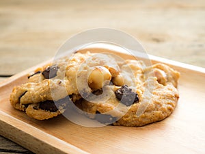 Cookies with chocolate and macadamia nuts. Placed on a wooden plate.
