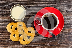 Cookies, coffee, spoon on saucer, condensed milk in bowl