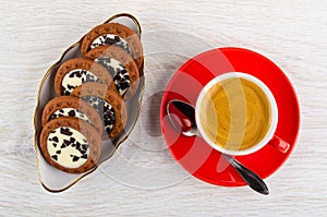 Cookies with cream, chocolate in plate, coffee espresso in cup, spoon on saucer on table. Top view