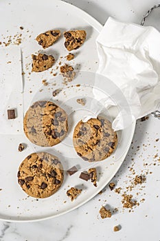 Cookies with dark chocolate chips and string on white plate.