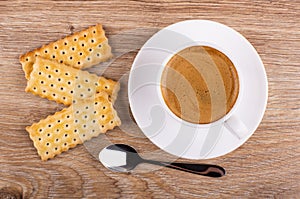 Cookies with filling, cup of coffee on saucer, spoon on table. Top view