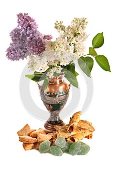 Cookies and fruit candy near to a vase with a lilac