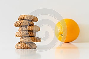 Cookies or fruit, cookies in focus, orange blurred, diet choice concept