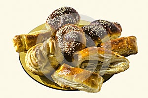 Cookies `Gata`, buns with sesame and Eclair lie on a ceramic plate on a white background