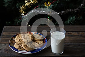 Cookies and a glass of milk on a Christmas tree background