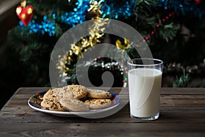 Cookies and a glass of milk on a Christmas tree background