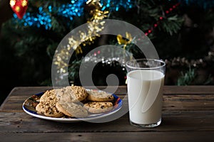 Cookies and a glass of milk on a Christmas tree background