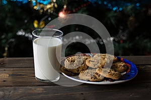 Cookies and a glass of milk on a Christmas tree background