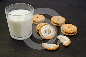 Cookies and a glass of milk on a dark wooden table .Sandwich cookies. Close-up.