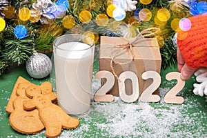 Cookies, a glass of milk for Santa on a table covered with snow on the background of Christmas decorations. New Year