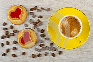 Cookies with jam hearts, coffee beans, cup with espresso on saucer on table. Top view