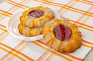Cookies with jam in saucer, cookie on napkin