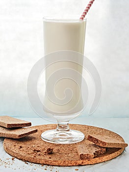 Cookies and milk drink in a tall glass with a tube on the table