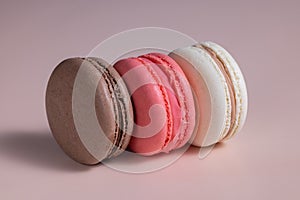 Cookies multicolored macaroons on a pink background of pink, dark brown and beige with shadows