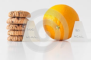 Cookies or orange fruit, diet choice concept, calorie count