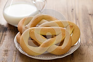 Cookies in plate and mlik on brown background