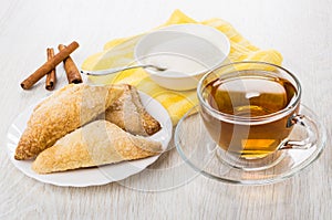 Cookies in plate, tea, sugar, spoon in bowl, cinnamon sticks