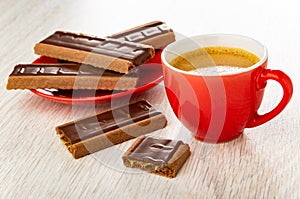 Cookies in saucer, pieces of cookie with chocolate and caramel, cup with coffee espresso on table