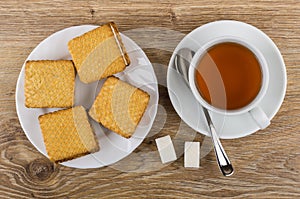 Cookies with souffle in plate, tea, spoon on saucer, sugar