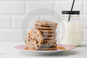 Cookies are spread out on a plate, a glass of fresh milk. Homemade cookies with chocolate chips.