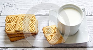 Cookies stacked and a cup of milk on a wooden background. Healthy snack