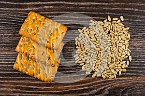 Cookies with sunflower seeds, heap of peeled seeds on dark wooden table. Top view