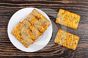 Cookies with sunflower seeds in plate and on dark wooden table. Top view