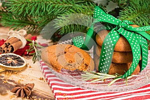 Cookies tied with green ribbon and Christmas decoration, on wooden surface.