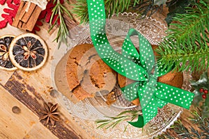 Cookies tied with green ribbon and Christmas decoration, on wooden surface.