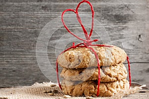 Cookies for Valentine`s Day with red heart shaped ribbon on wood