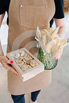 Cookies in a windowed box and on sticks, held by confectioner in his hands