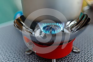 Cooking in an aluminum pot meals on a portable gas burner on a background of camping in the woods. Close-up of portable gas burner