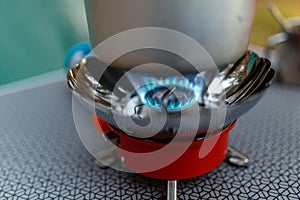 Cooking in an aluminum pot meals on a portable gas burner on a background of camping in the woods. Close-up of portable gas burner