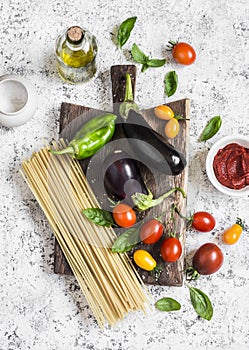 Cooking background. Raw ingredients for making pasta - spaghetti, eggplant, tomatoes, pepper, olive oil, tomato sauce and basil on