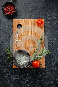 cooking background with wooden cutting board with spices, tomatoes and herbs. Long banner format. top view