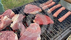 Cooking barbecue, steaks and sausages. Summer holidays and vacations. Raw red meat steaks and sausages are grilled on a charcoal