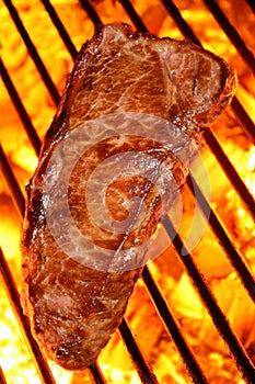 Cooking a beef steak on a fire hot barbecue grill