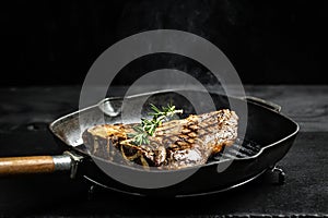 Cooking beef steak on frying grill pan on black. Food recipe background. T-bone or aged wagyu porterhouse grilled beef steak.