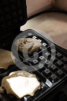 cooking Belgian waffles in a waffle iron. Pour in the dough.