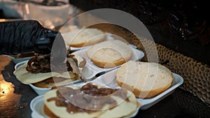 cooking burgers. Close-up. Chef adds delicious ingredients to burger, as fresh cucumbers, tomatoes, juicy, grilled beef