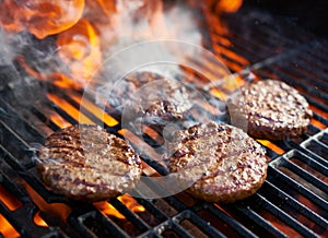 Cooking burgers on hot grill with flames