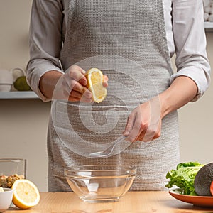 Cooking. Chef crushes lemon juice, in the process of a vegetarian salad in the home kitchen. Light background. Restaurant menu,