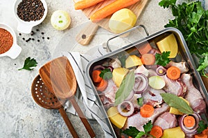 Cooking chicken bouillon or roast in cooking pan or pot with vegetables potatoes, carrots and herbs on kitchen grey concrete