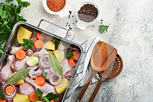 Cooking chicken bouillon or roast in cooking pan or pot with vegetables potatoes, carrots and herbs on kitchen grey concrete