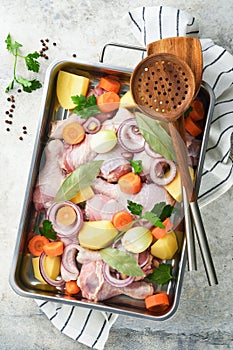 Cooking chicken bouillon or roast in cooking pan or pot with vegetables potatoes, carrots and herbs on kitchen grey concrete