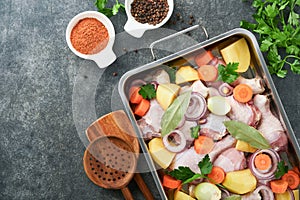 Cooking chicken bouillon or roast in cooking pan or pot with vegetables potatoes, carrots and herbs on kitchen grey concrete