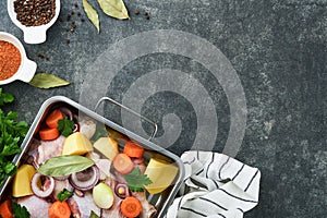 Cooking chicken bouillon or roast in cooking pan or pot with vegetables potatoes, carrots and herbs on kitchen grey concrete